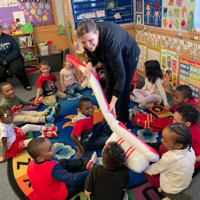 dental hygienist in a classroom playing with kids and a giant blowup toothbrush