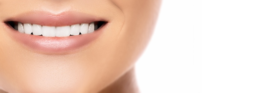 Zoom-in a a women smiling who has straight white teeth in front of a white background.