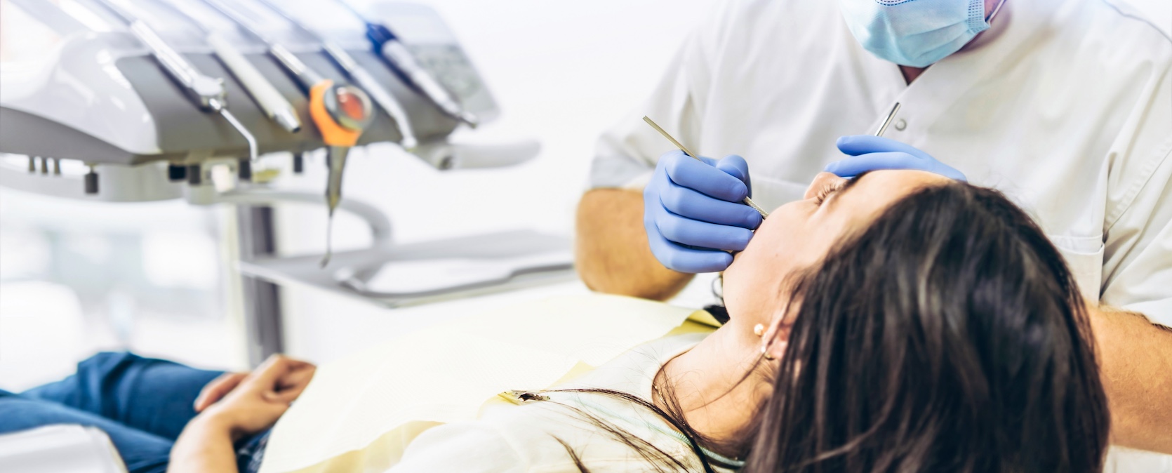 A dentist with a patient in a dental chair is providing manipulations for all-on-4 dental implants.